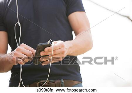 Picture - Young man with smartphone and earphones. Fotosearch
