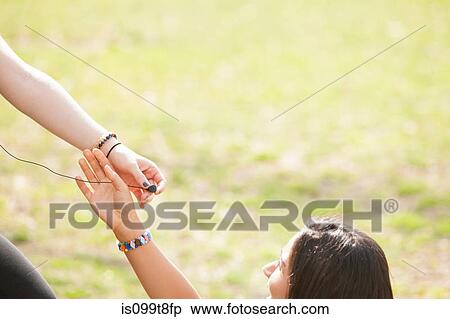 Stock Photography - Young people sharing earphones. Fotosearch