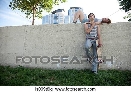 Young woman lying on wall with skateboarder View Large Photo Image Stock Photography - Young woman lying on wall with skateboarder. Fotosearch