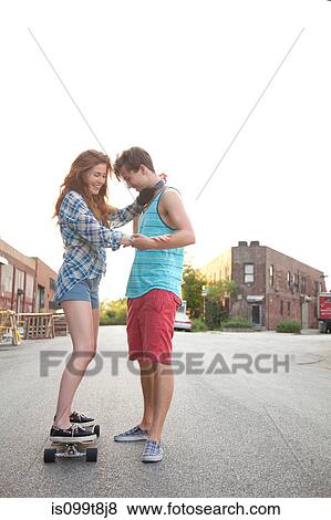 Young woman on skateboard with boyfriend View Large Photo Image Stock Photo - Young woman on skateboard with boyfriend. Fotosearch