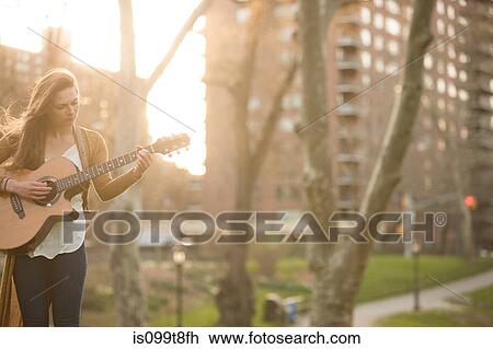 Young woman playing guitar in the park View Large Photo Image Stock Image - Young woman playing guitar in the park. Fotosearch
