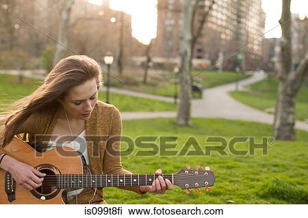 Young woman playing guitar in the park View Large Photo Image Stock Image - Young woman playing guitar in the park. Fotosearch
