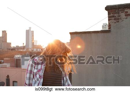 Young woman shaking hair on city rooftop View Large Photo Image Stock Photograph - Young woman shaking hair on city rooftop. Fotosearch