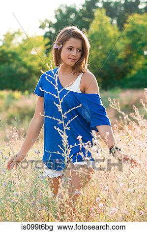 Young woman walking in field View Large Photo Image Stock Image - Young woman walking in field. Fotosearch