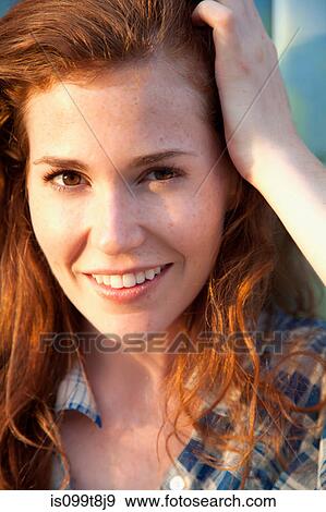 Stock Photo - Young woman with hand in hair, portrait. Fotosearch