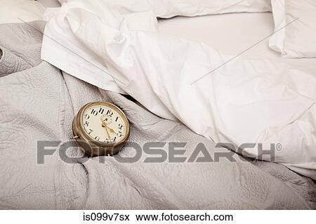 Stock Photo - Alarm clock on bed. Fotosearch