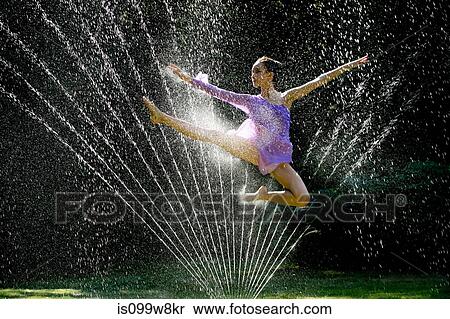 Stock Photography - Ballerina jumping over water sprinkler. Fotosearch