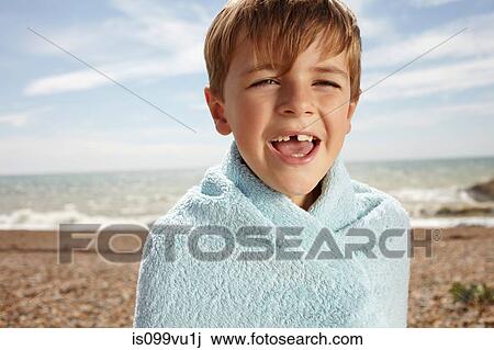 Stock Image - Boy at the beach, wrapped in a towel. Fotosearch