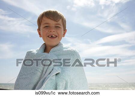 Stock Image - Boy by the sea, wrapped in a towel. Fotosearch