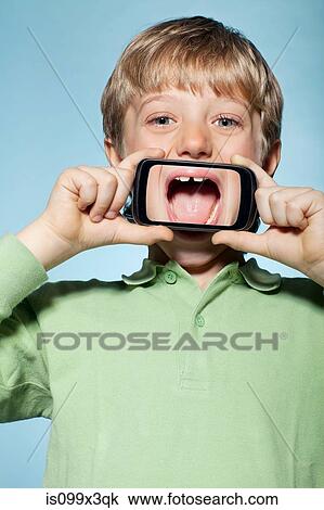 Stock Image - Boy holding smartphone over mouth. Fotosearch