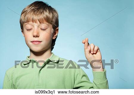 Stock Image - Boy with fingers crossed. Fotosearch