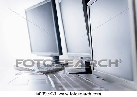 Stock Photo - Computer screens and laptop on desk. Fotosearch