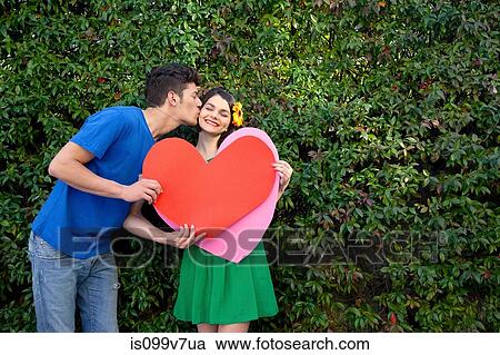 Couple holding heart shape, man kissing woman View Large Photo Image Stock Image - Couple holding heart shape, man kissing woman. Fotosearch