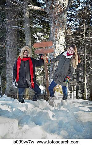 Stock Photo - Couple holding wooden sign in forest. Fotosearch
