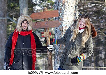 Stock Photograph - Couple holding wooden sign in forest. Fotosearch