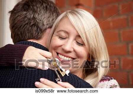 Stock Photography - Couple hugging, woman holding house keys. Fotosearch