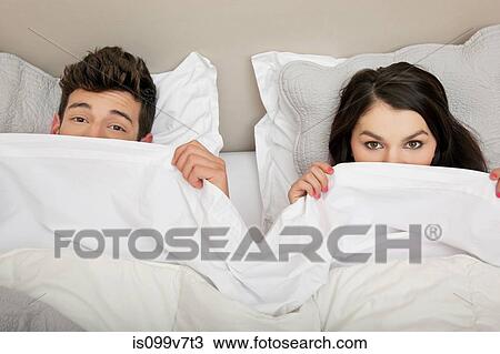 Couple in bed peeking behind duvet View Large Photo Image Stock Image - Couple in bed peeking behind duvet. Fotosearch