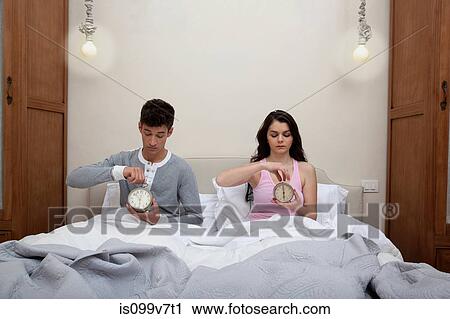 Couple in bed setting alarm clocks View Large Photo Image Stock Image - Couple in bed setting alarm clocks. Fotosearch