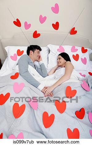Couple in bed with heart shapes on bedclothes View Large Photo Image Stock Image - Couple in bed with heart shapes on bedclothes. Fotosearch
