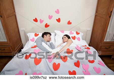 Couple in bed with heart shapes on bedclothes View Large Photo Image Stock Photo - Couple in bed with heart shapes on bedclothes. Fotosearch