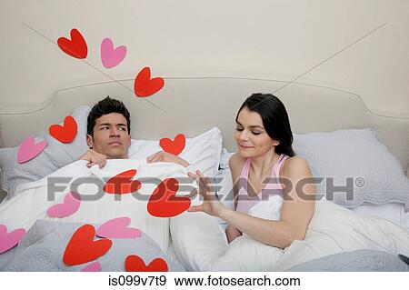 Stock Photo - Couple in bed with heart shapes on bedclothes. Fotosearch