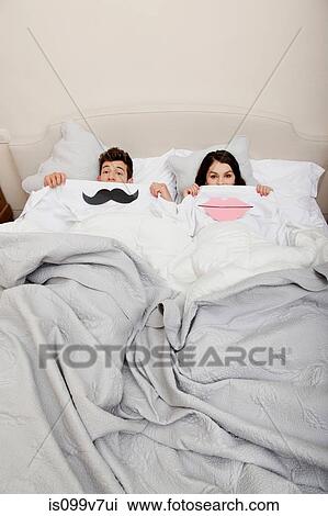 Stock Image - Couple in bed with lips and moustache. Fotosearch