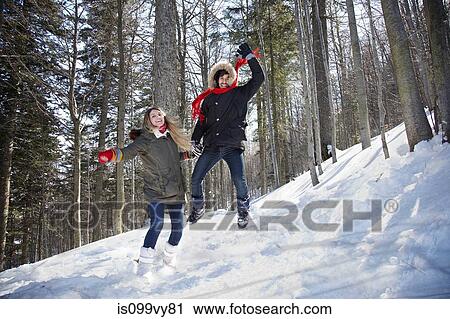 Stock Image - Couple jumping in snow. Fotosearch