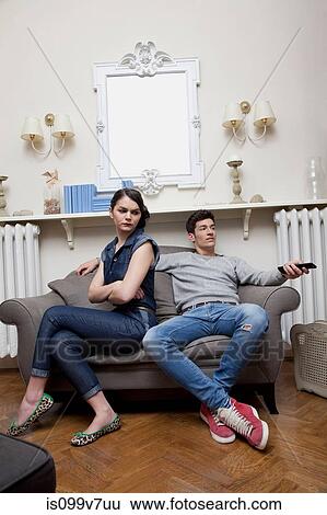 Stock Photograph - Couple on sofa, woman ignoring man. Fotosearch