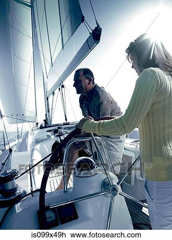 Stock Image - Couple sailing a yacht. Fotosearch