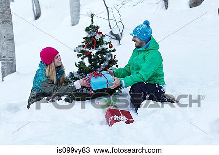 Couple sitting by christmas tree with gifts View Large Photo Image Stock Image - Couple sitting by christmas tree with gifts. Fotosearch