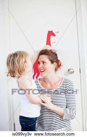 Stock Photo - Daughter measuring mother on height chart. Fotosearch