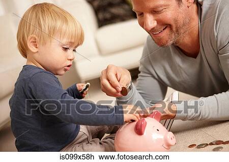 Stock Image - Father and son putting coins in piggy bank. Fotosearch