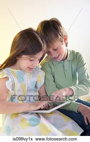 Stock Photo - Girl and boy using digital tablet. Fotosearch