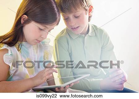 Girl and boy using digital tablet with bright light View Large Photo Image Stock Image - Girl and boy using digital tablet with bright light. Fotosearch