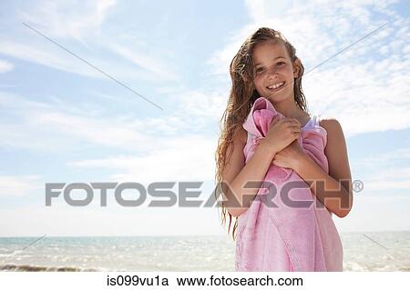 Stock Image - Girl by the sea, wrapped in towel. Fotosearch