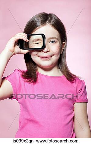 Girl holding smartphone over eye View Large Photo Image Picture - Girl holding smartphone over eye. Fotosearch