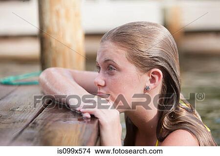 Girl in water, leaning on jetty View Large Photo Image Picture - Girl in water, leaning on jetty. Fotosearch