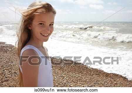 Girl on shingle beach by the sea, smiling at camera View Large Photo Image Picture - Girl on shingle beach by the sea, smiling at camera. Fotosearch
