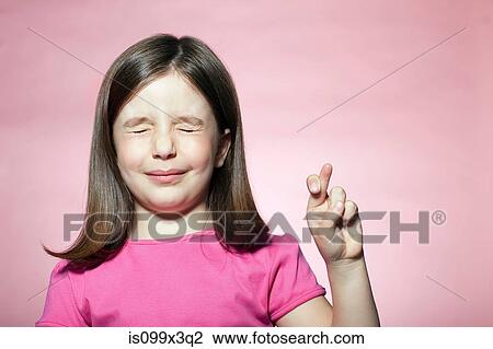 Stock Image - Girl with fingers crossed. Fotosearch
