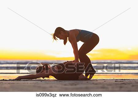 Instructor helping woman into yoga pose on beach View Large Photo Image Stock Photo - Instructor helping woman into yoga pose on beach. Fotosearch