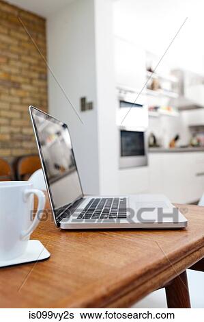 Laptop and mug on table View Large Photo Image Stock Photograph - Laptop and mug on table. Fotosearch