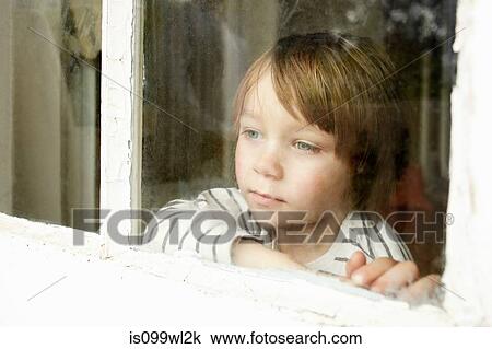 Stock Image - Little boy looking through window. Fotosearch