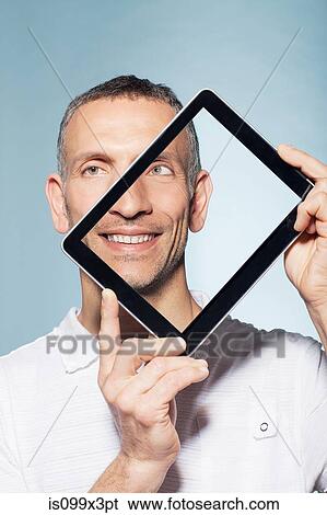 Man covering half his face with digital tablet View Large Photo Image Stock Photograph - Man covering half his face with digital tablet. Fotosearch