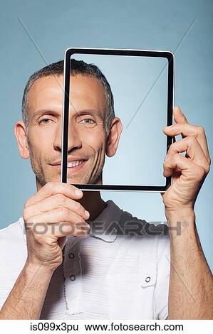 Man covering half his face with digital tablet View Large Photo Image Stock Photograph - Man covering half his face with digital tablet. Fotosearch