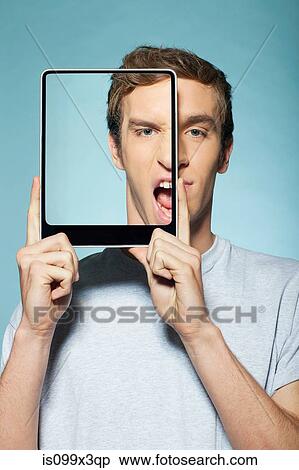 Man covering half his face with digital tablet View Large Photo Image Stock Photography - Man covering half his face with digital tablet. Fotosearch