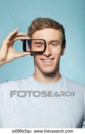 Stock Photograph - Man holding smartphone over eye. Fotosearch