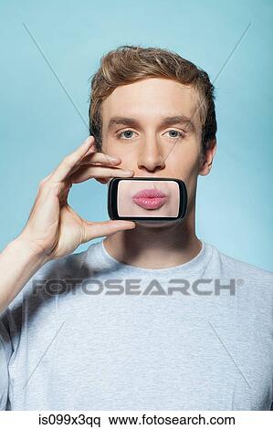 Man holding smartphone over mouth View Large Photo Image Stock Photography - Man holding smartphone over mouth. Fotosearch