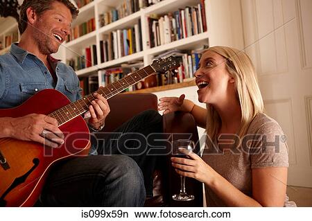 Picture - Man playing guitare, woman singing. Fotosearch