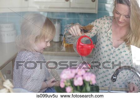 Stock Photograph - Mother and daughter washing up, mother pouring water. Fotosearch