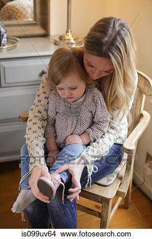 Mother helping daughter put on shoe View Large Photo Image Picture - Mother helping daughter put on shoe. Fotosearch
